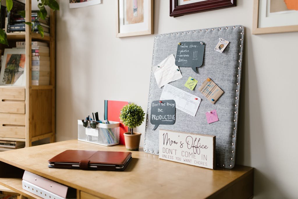 A neat and stylish home office space featuring a pin board, desk, and decor.